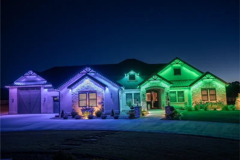 Colorful blue and green accent lighting outlines a one-story home under a dark sky