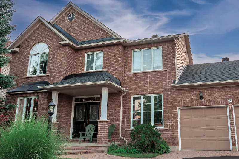 Traditional brick home with columns and arched window on sunny day