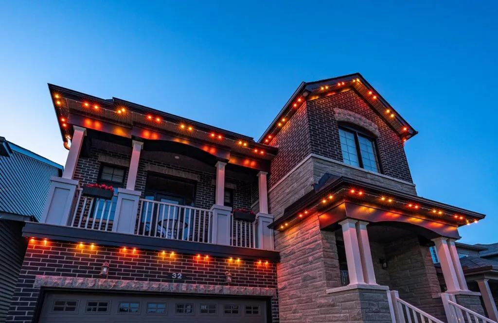 Brick home lit by Brilliant By Night roof lights in warm multicolor tones