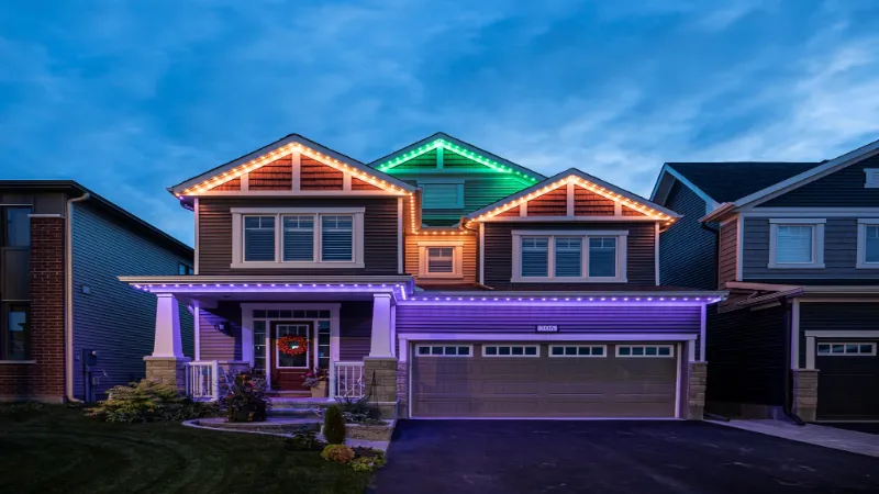 Roofline of a two story house glows with green, purple, and orange Permanent Holiday Lights in Colorado