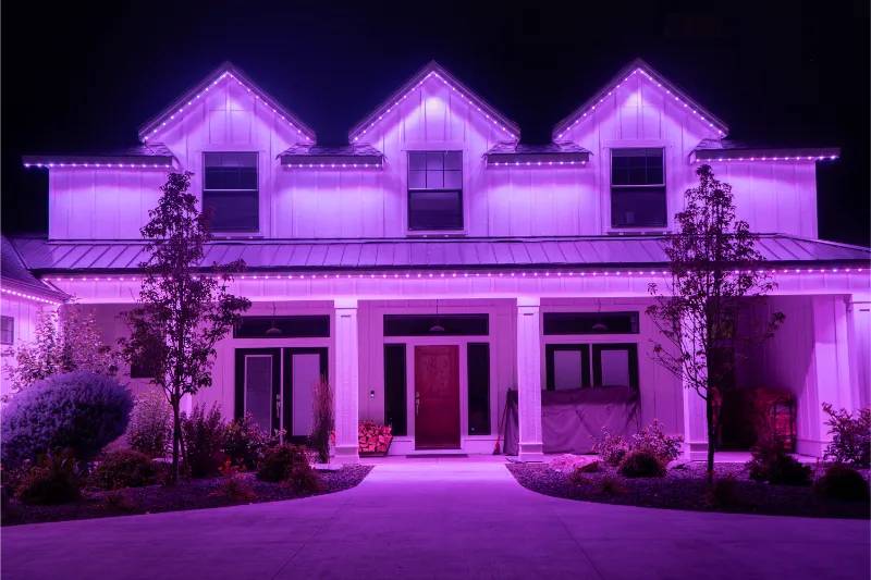 White Two-story House glows entirely in purple from Brilliant By Night roofline lights