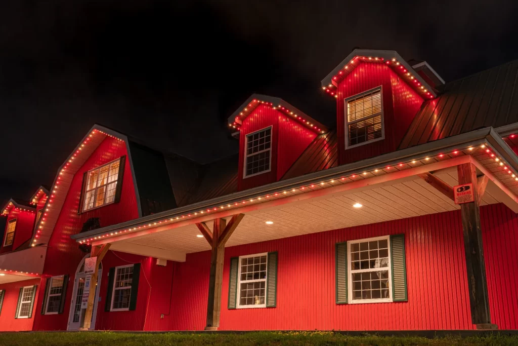 Brilliant By Night Red and white roofline lights glow on barn-shaped structure at night