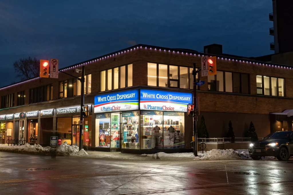 Roof lighting from Brilliant By Night highlights corner pharmacy storefront on a snowy evening