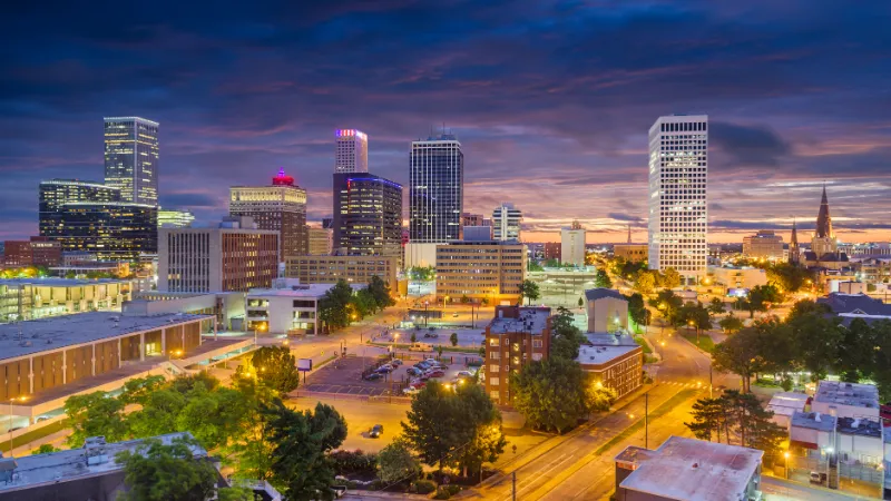 Downtown skyline of Tulsa, Oklahoma glows beneath a dramatic, colorful evening sky