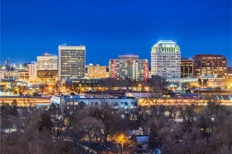 Colorado Springs City skyline shines brightly against a deep blue evening sky