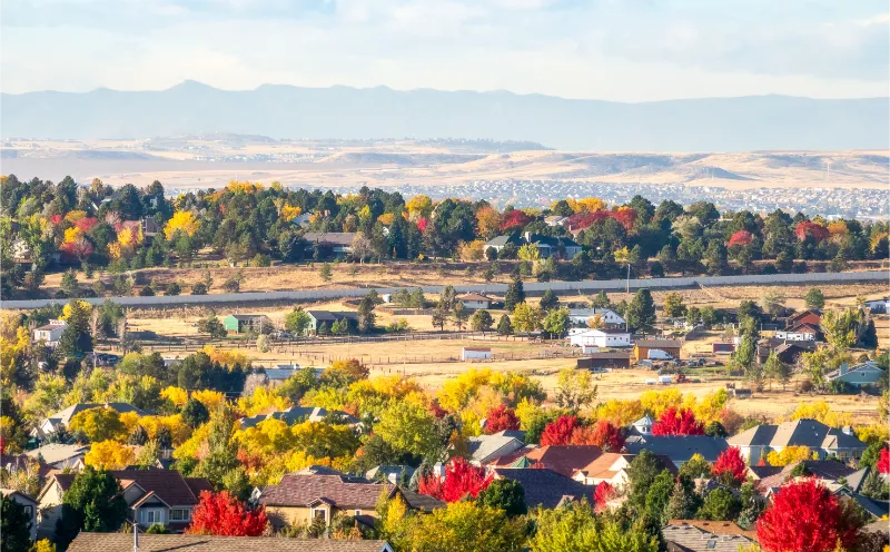 Scenic view of homes and autumn trees in Centennial, Colorado with open land and distant hills
