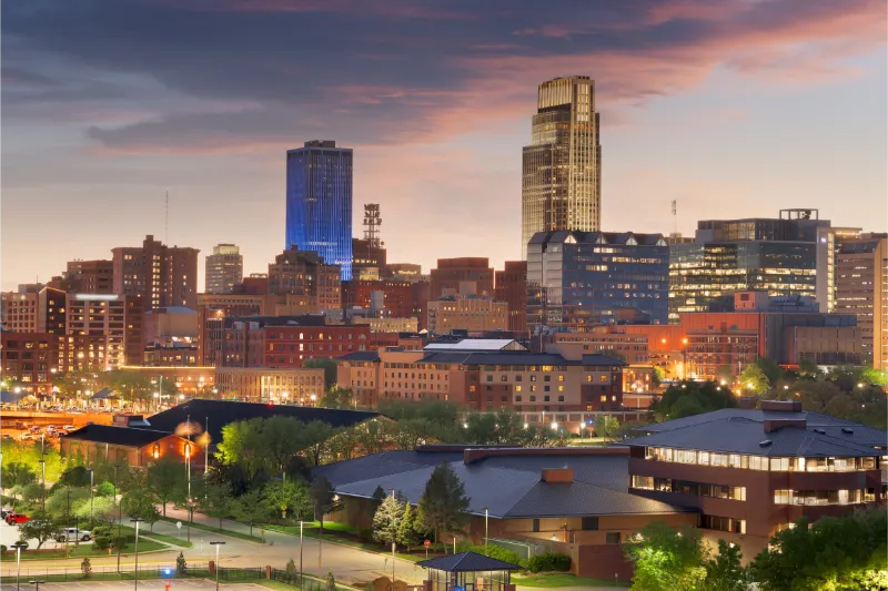 Lit city skyline at sunset with modern towers and historic buildings in Omaha, Nebraska