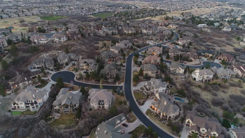 Winding road curves through a neighborhood of large suburban homes in Castle Pines, Colorado